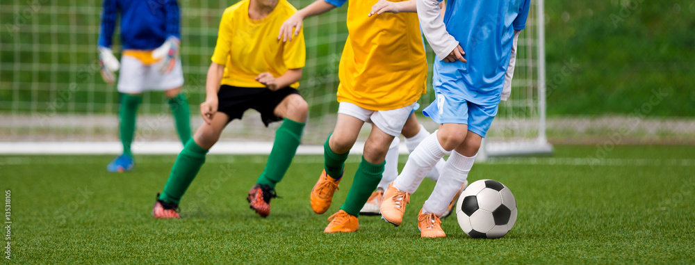 Football Soccer Match for Children. Kids Playing Soccer Game Tournament. Boys Running and Kicking Football. Youth Soccer Goalkeeper in the Background Football Soccer Match for Children. Kids Playing Soccer Game Tournament. Boys Running and Kicking Football. Youth Soccer Goalkeeper in the Background