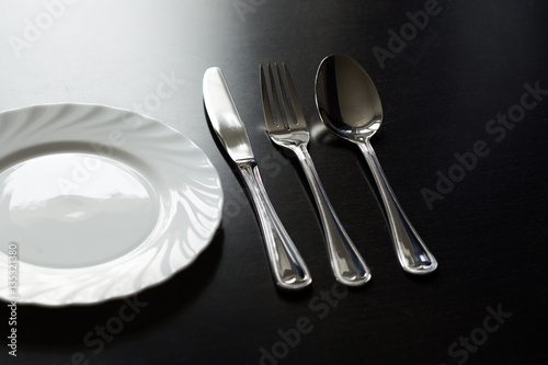 Cutlery on a black background. Fork, spoon, knife, plate.