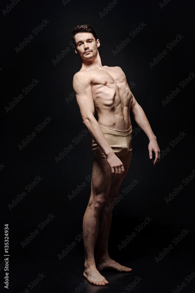 Involved young dancer standing in the black room