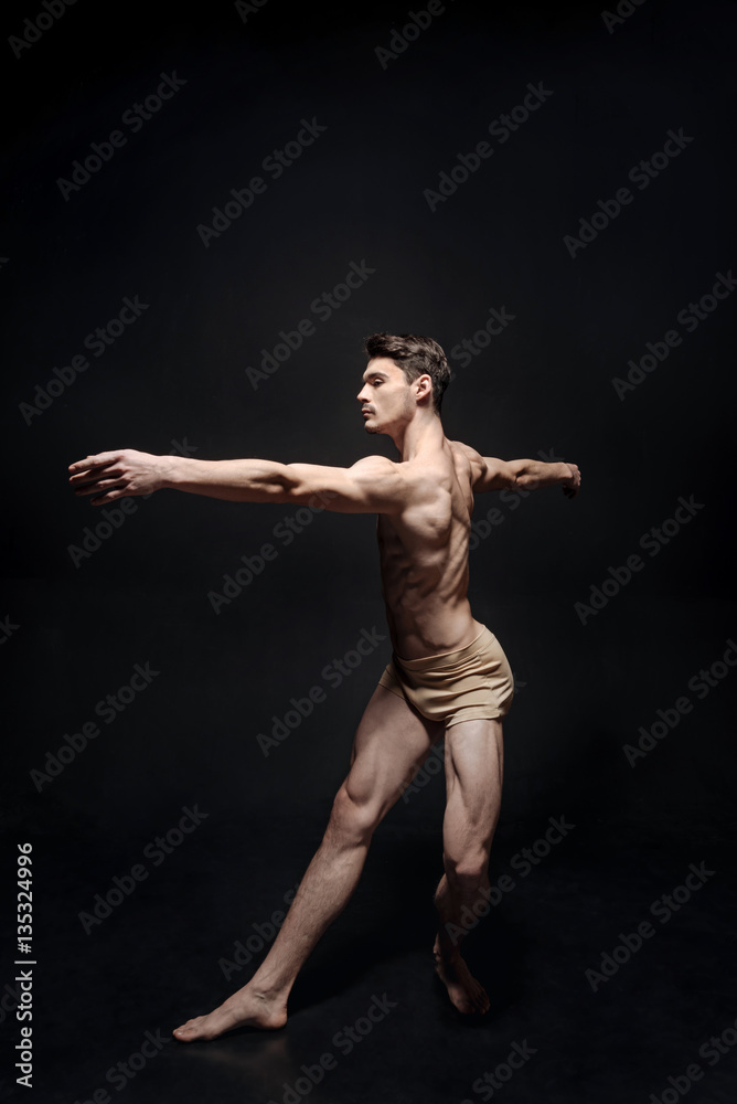 Graceful male dancer acting in the black studio