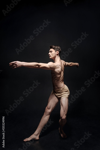 Fototapeta Naklejka Na Ścianę i Meble -  Graceful male dancer acting in the black studio
