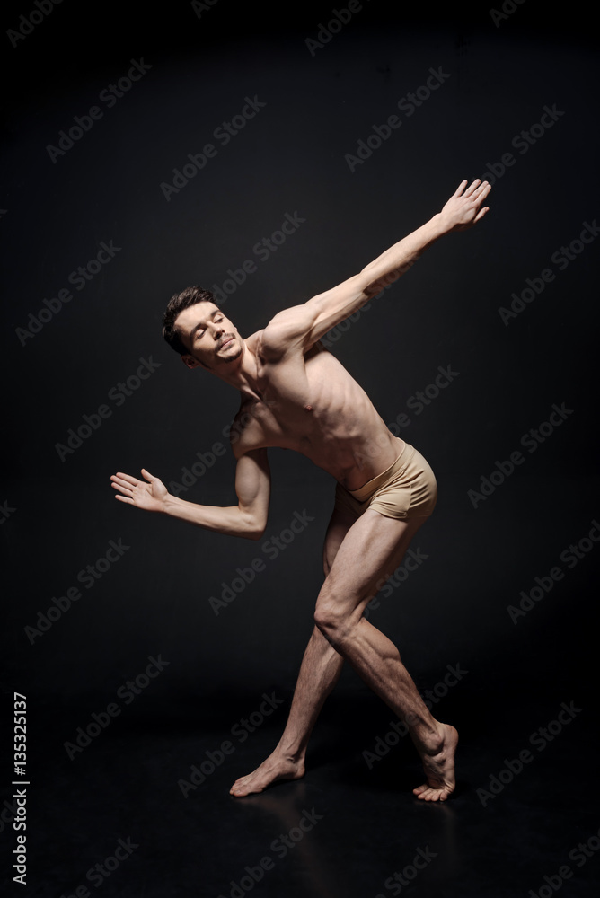 Talented dancer showing his flexibility in the black colored studio