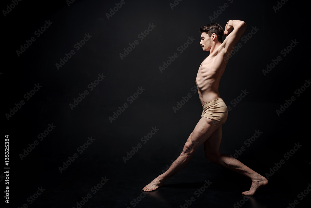 Inventive young man dancing in the black colored room