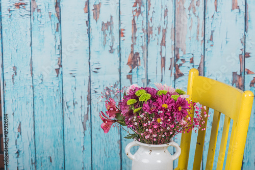 Bouquet of flowers in vintage vase sitting on yellow chair © nsc_photography