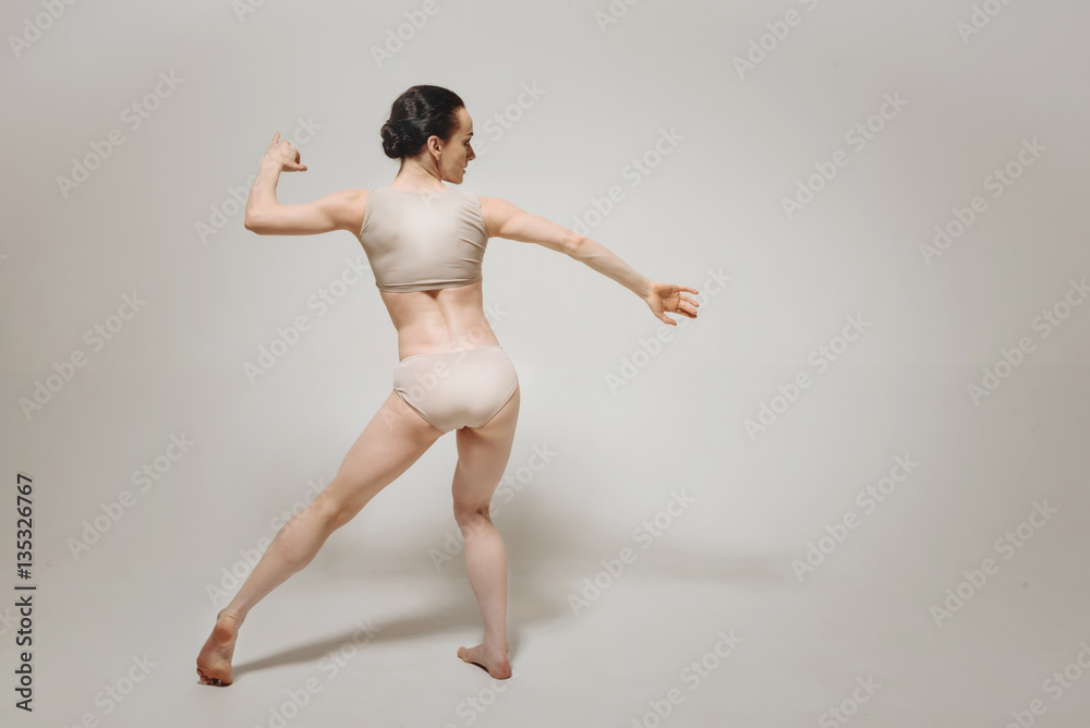 Flexible young ballet dancer performing near the white wall