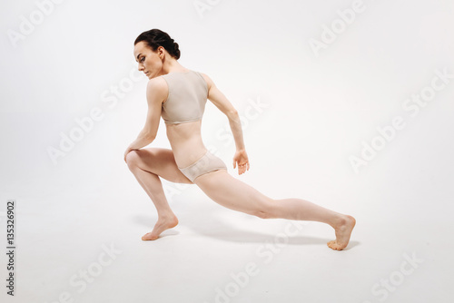 Flexile young gymnast performing in the white colored studio