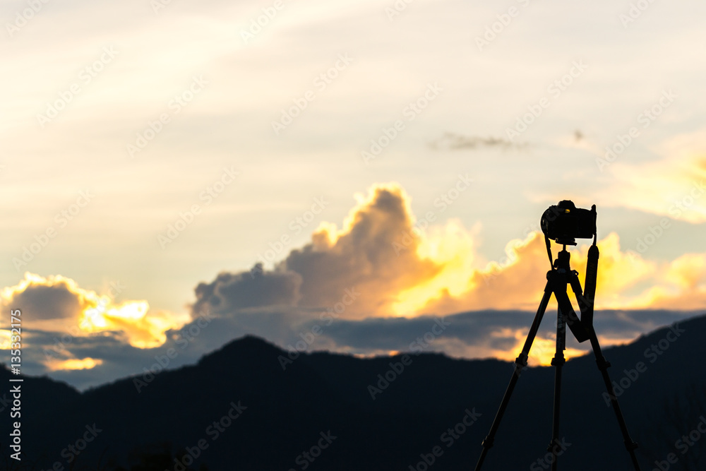 silhouette of camera on tripod with sunrise sky