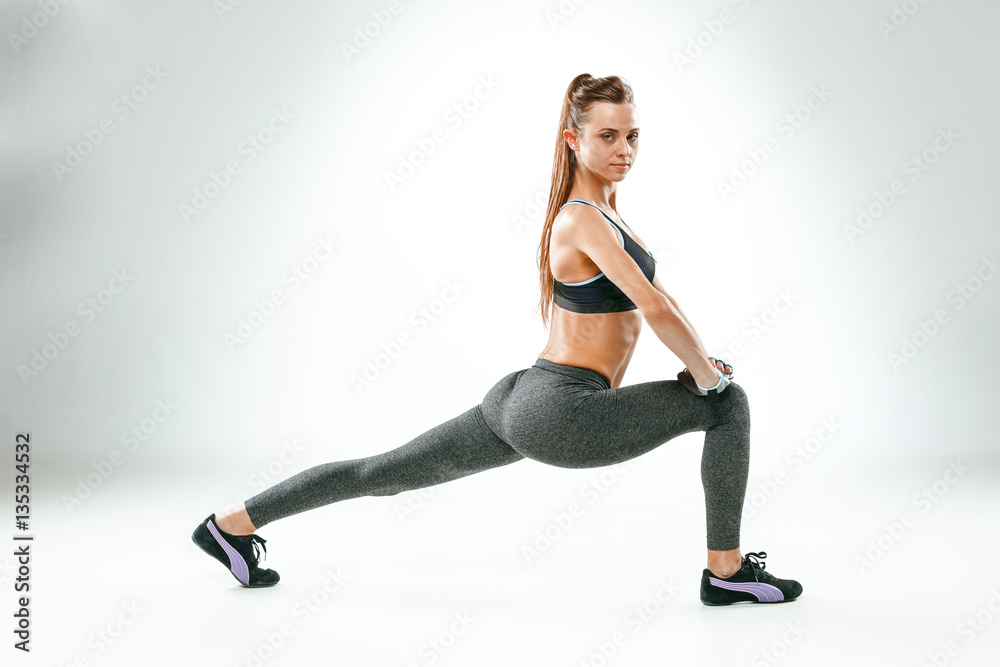 Beautiful slim brunette doing some stretching exercises in a gym