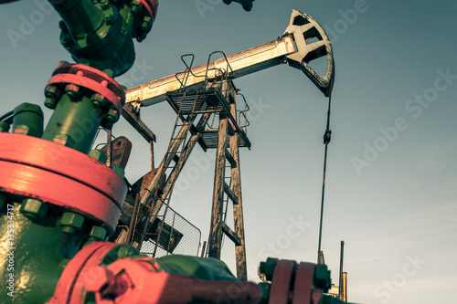 Oil pump jack and wellhead in the oilfield. Oil and gas concept.