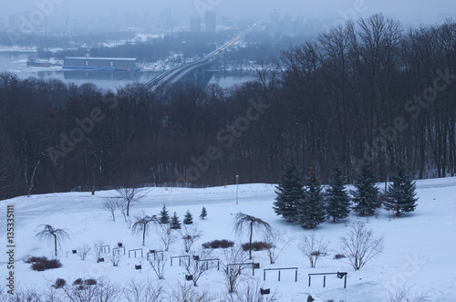 Frosty winter morning in the park. In the background is seen the river Dnepr and buildings are in the mist on the left bank. Kiev. Ukraine © evgenij84