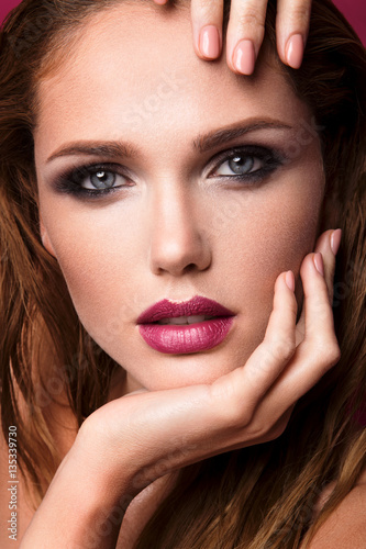Glamour portrait of beautiful girl model with makeup and romantic wavy hairstyle. Fashion shiny highlighter on skin  sexy gloss lips make-up and dark eyebrows.