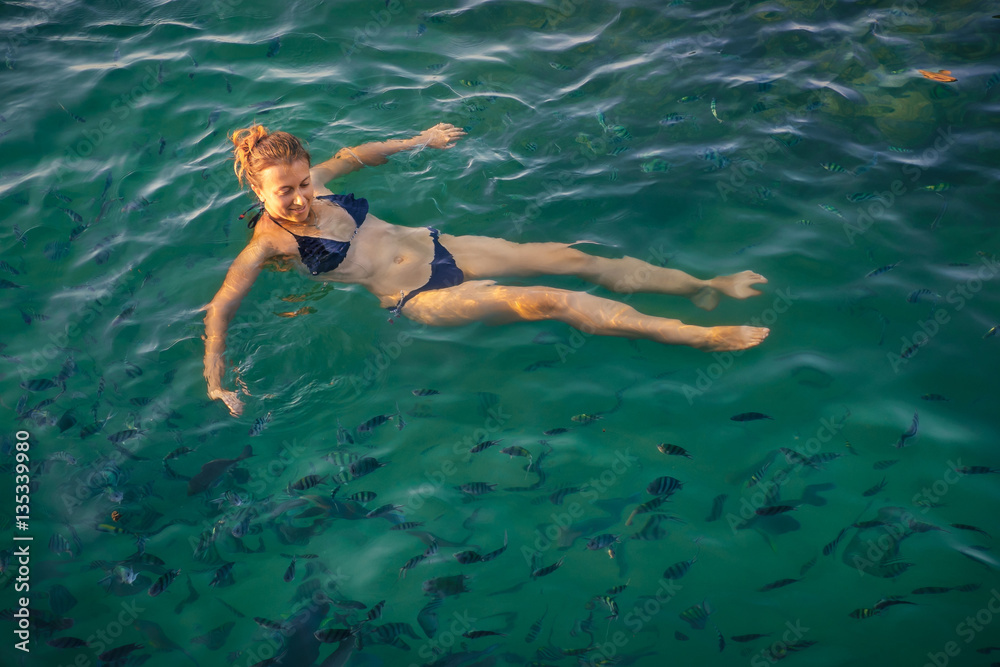 Woman swimming  in clear sea water with fishes in Phangan