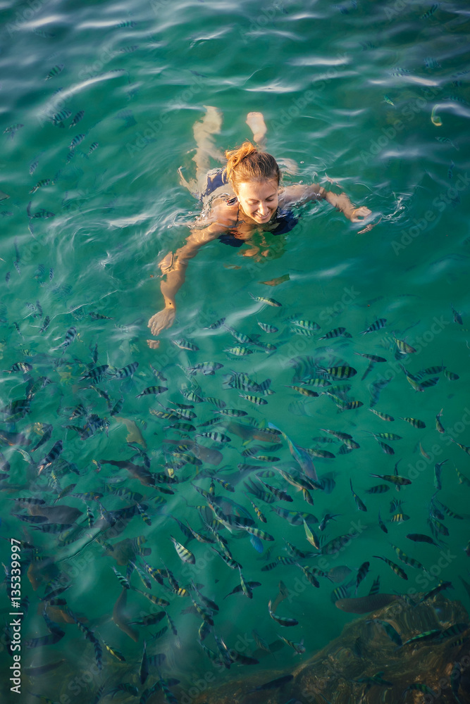Woman swimming  in clear sea water with fishes in Phangan
