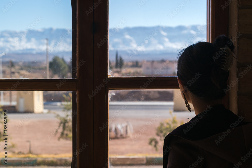 Woman looking through the old window
Woman looking through the old window
