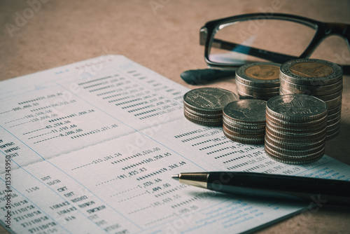 row of coins ,pen and eye glasses on account book in finance and