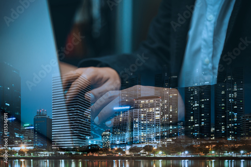 Double exposure of businessman  using laptop and city in busines