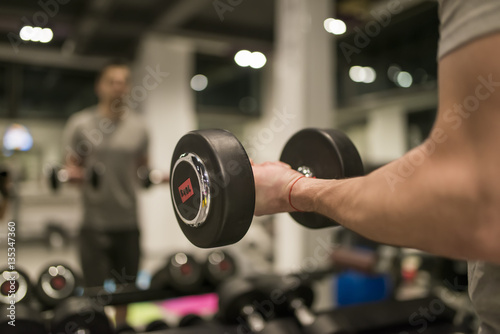 Muscular man training with red dumbbell in the gym