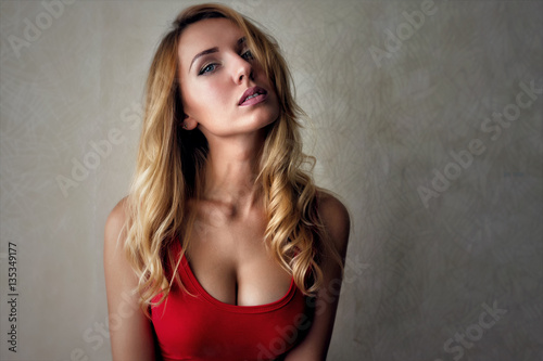 Portrait of curly cute young woman with beauty blonde hair style and perfect body in red bodysuit or t-shirt