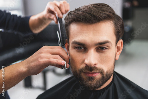 Photographie Skillful hairdresser cutting male hair