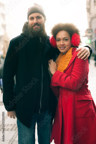 Romantic multiethnic couple in love hugging on the street