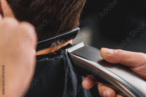 Skillful barber using shearer for haircut photo