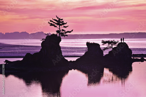 Sunset of Beach with rock formations and pink and purple tones of light/Sunset of pink and purple colors on beach in Siletz Bay, Oregon with silhouettes of rock and hiker photo