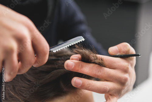 Competent hairdresser doing haircut by special tool