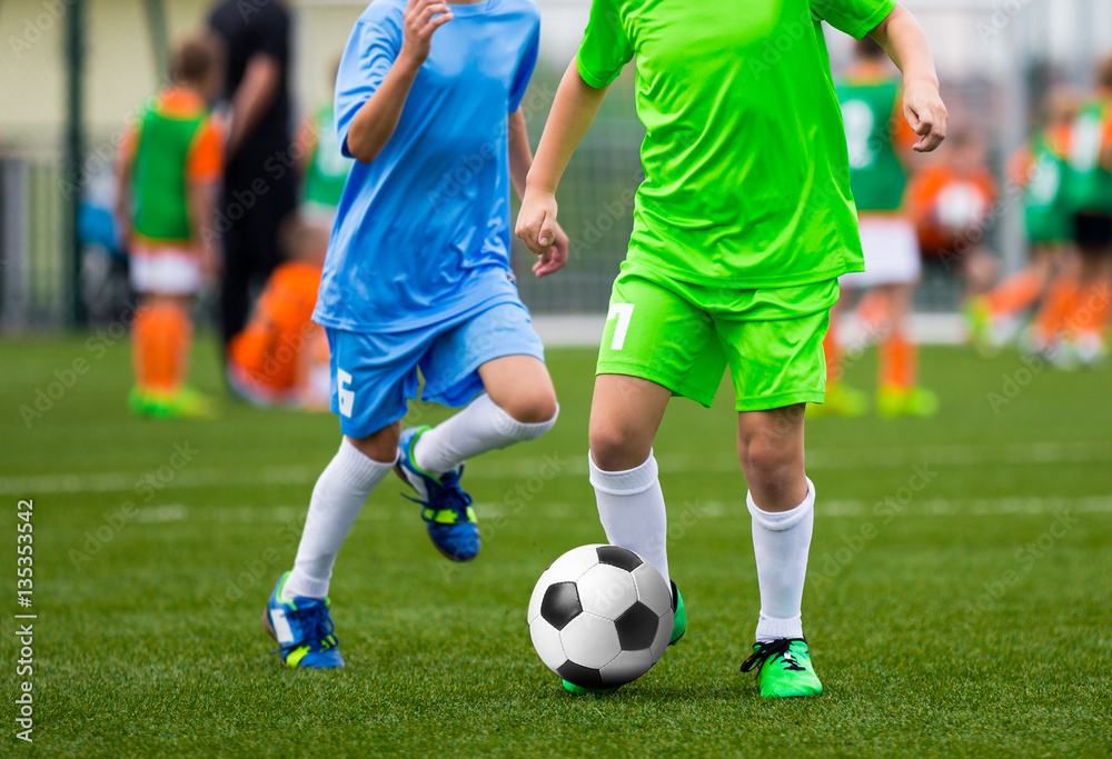 Youth Soccer Players. Boys Kicking Football Ball on the Field. Football Tournament for Kids. Soccer Pitch in the Background