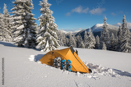 Yellow tent and snowshoes standing side by side