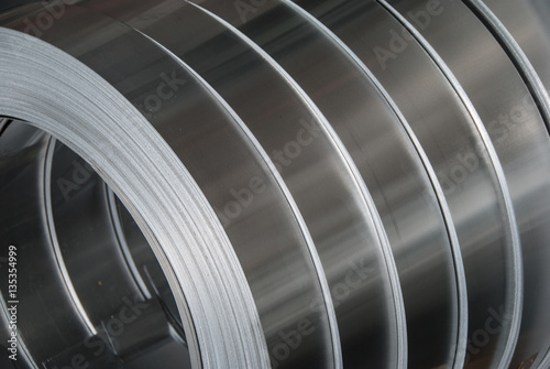 Aluminum sheet metal coils narrowed to size and stacked for packaging. Metal industry background photo