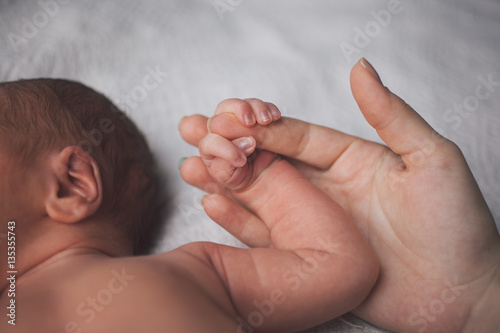 Parent holding in the hands a palm of newborn baby. photo