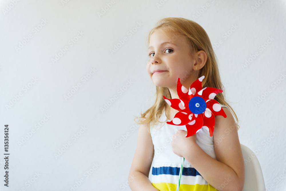 Φωτογραφία Portrait of pretty little girl with red windmill at summer day