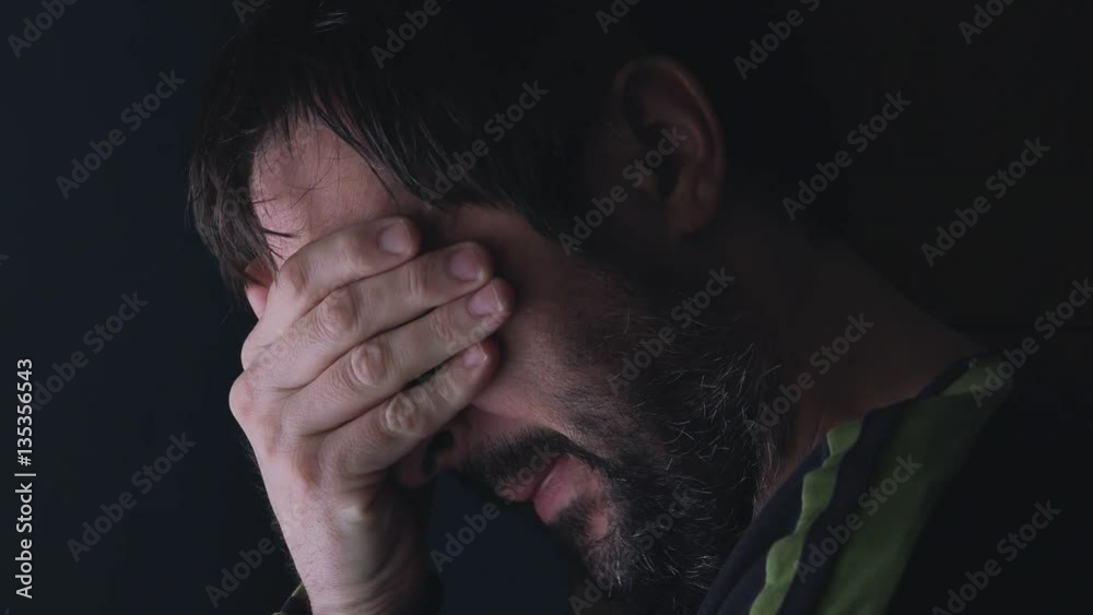 Grief, man covering face and crying, low key portrait by the window
