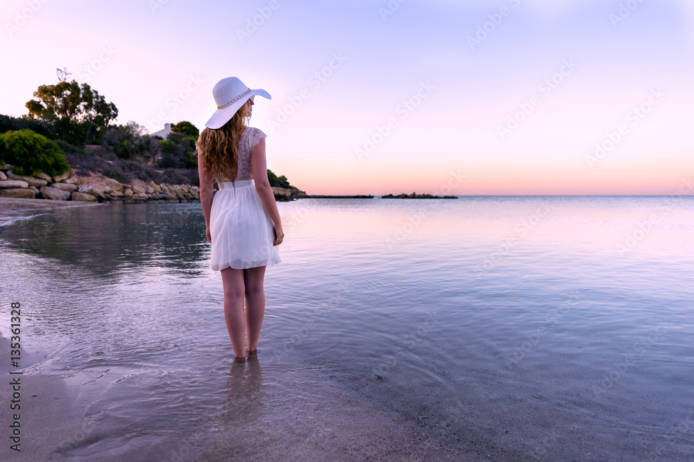Woman walking down the beach at sunset. Beautiful Sunset sea view in Cyprus island