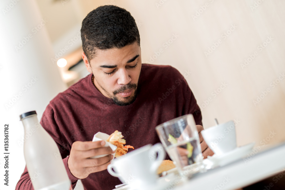 Young handsome man eating at a restaurant bar