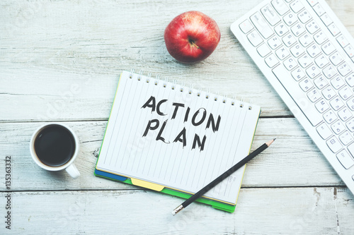 action plan text on notebook with keyboard and coffee on table