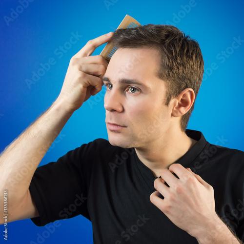 tudio portrait of a handsome young man combs her hair photo