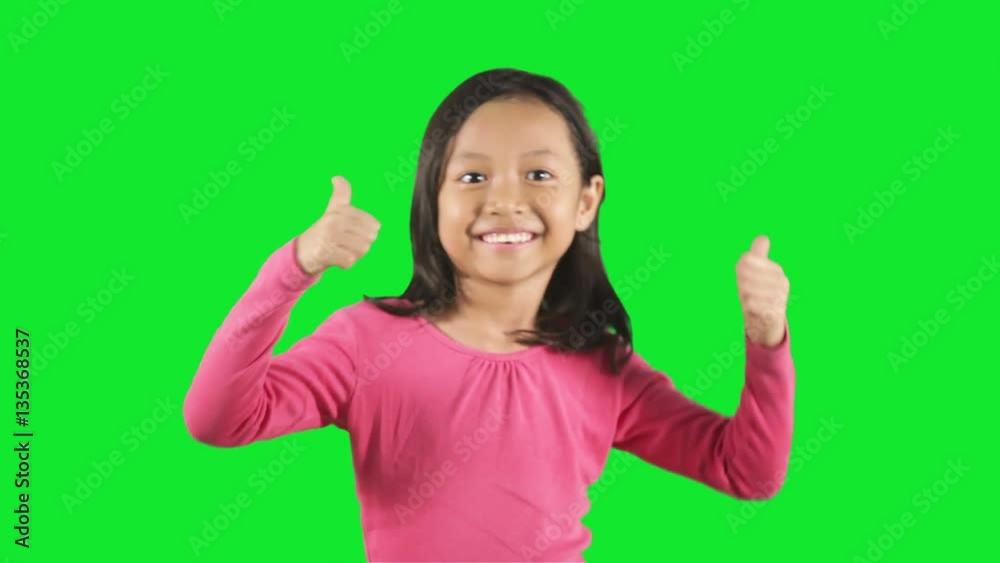 Asian little girl standing in the studio while smiling at the camera and showing thumbs up