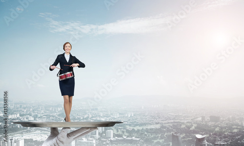 Attractive businesswoman on metal tray playing drums against cityscape background