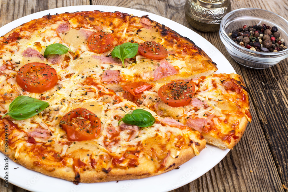 Pizza with ham, cheese, tomatoes and basil