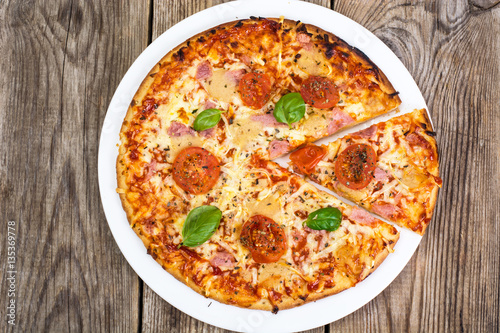 Pizza with ham, cheese, tomatoes and basil