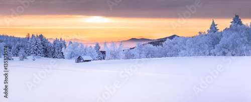 Panorama of an idyllic white winter landscape with a little wooden hut in background