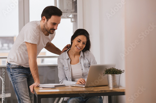 Happy modern couple surfing the net and working on laptop at hom