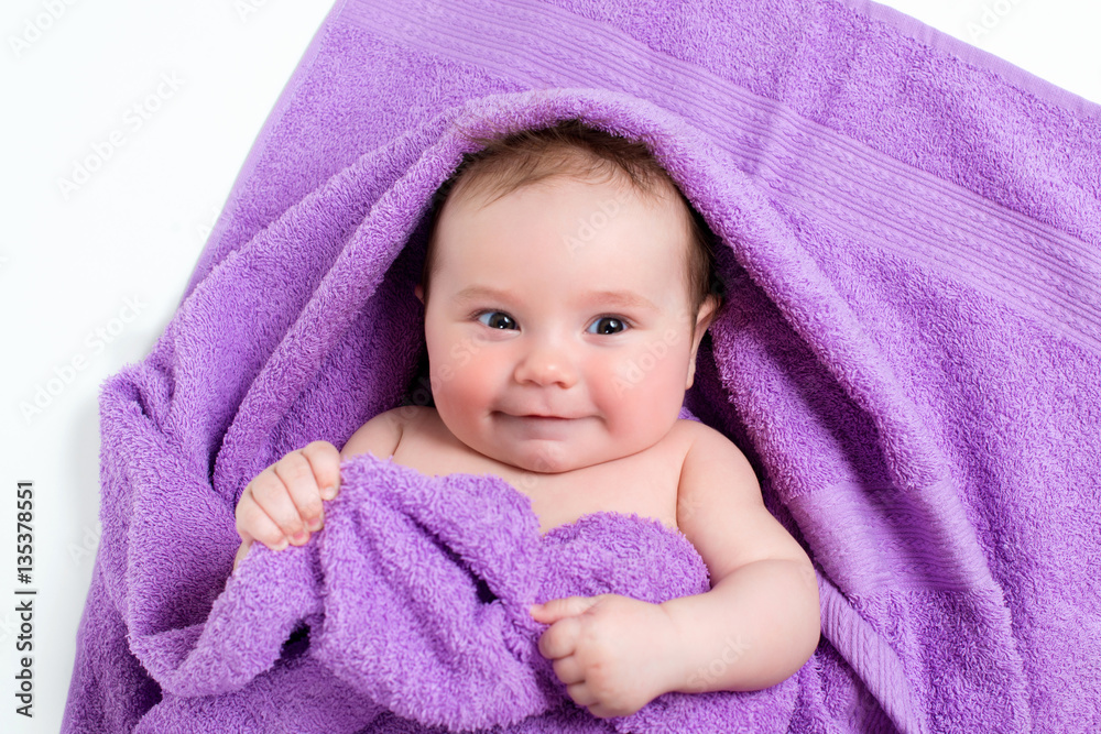 Newborn baby lying down and smiling in a purple towel Newborn baby lying down and smiling in a purple towel
