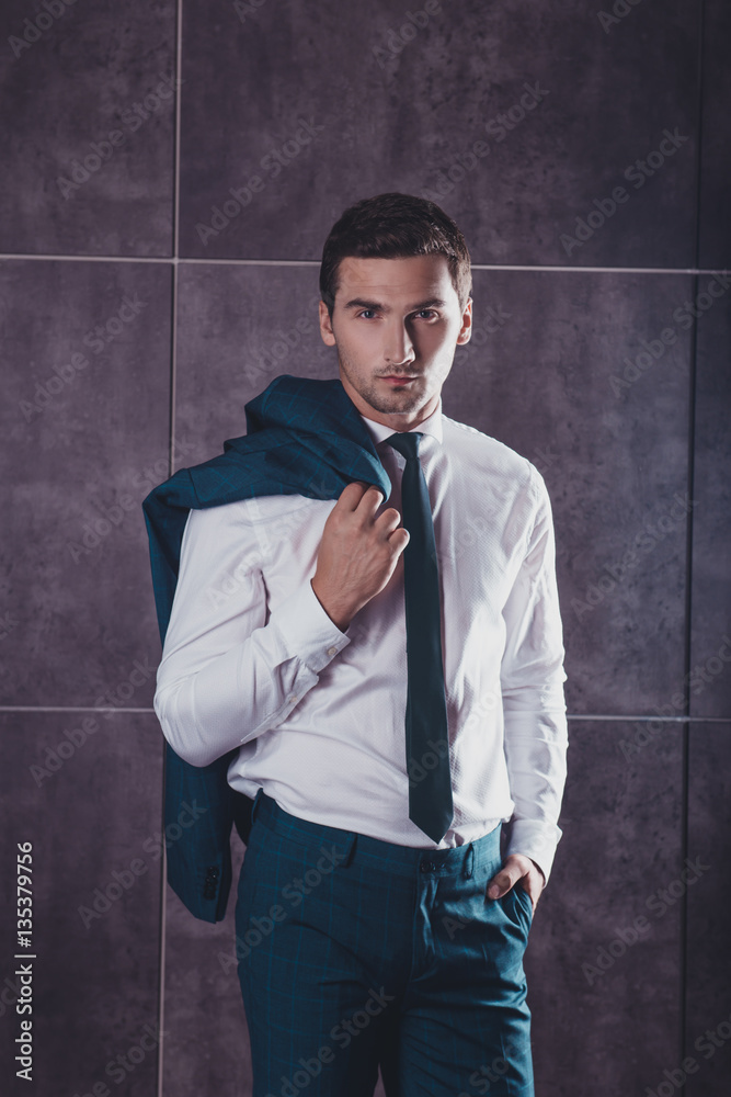 Stylish handsome young man holding jaket on shoulder