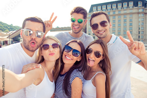 Six happy successful young people having fun and making selfie © deagreez
