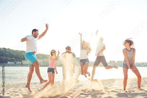 Carefree young people having fun and jumping on the seaside