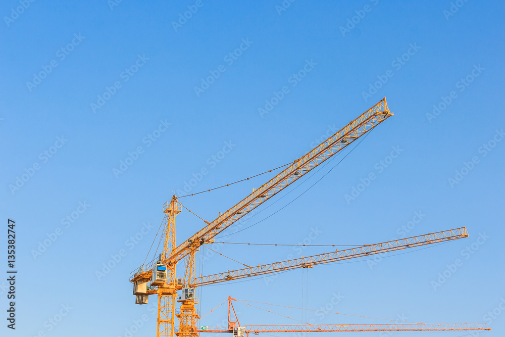 Industrial construction cranes against the blue sky in construction site, tool of building industry