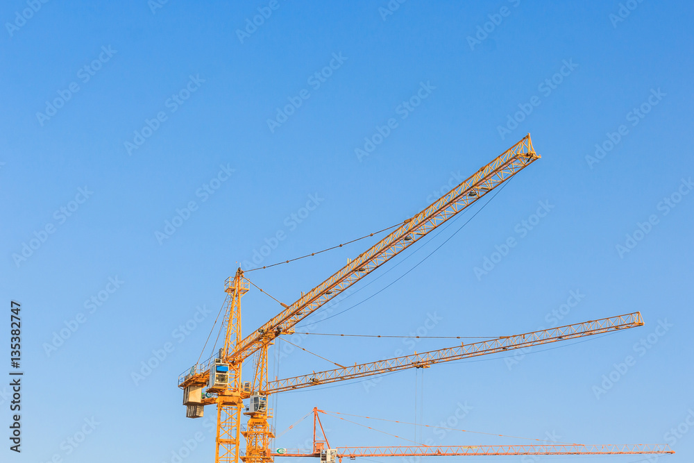 Industrial construction cranes against the blue sky in construction site, tool of building industry Industrial construction cranes against the blue sky in construction site, tool of building industry