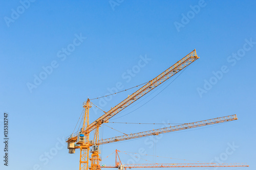 Industrial construction cranes against the blue sky in construction site, tool of building industry